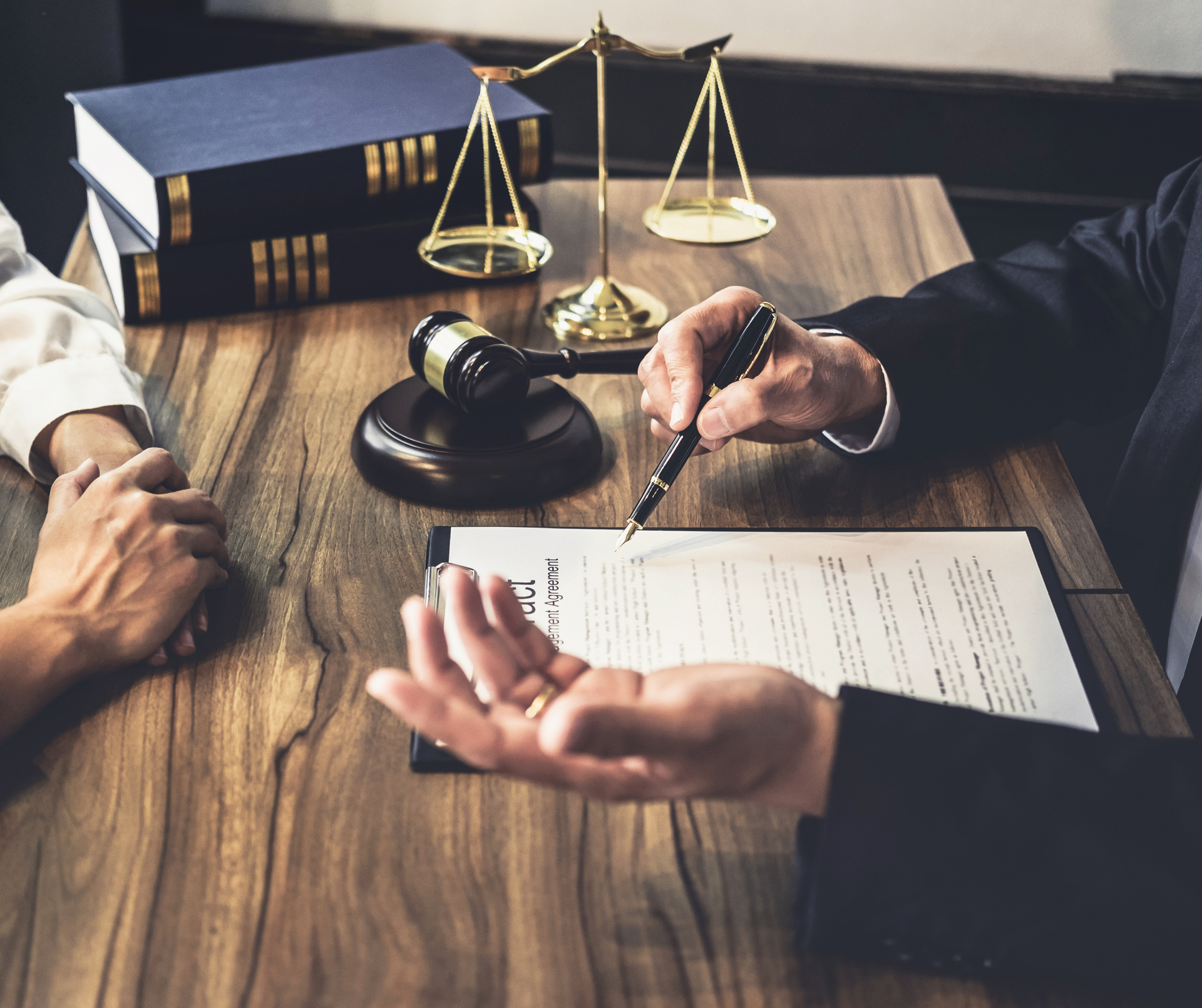 Two people are sitting at a table with a judge 's gavel and scales of justice.