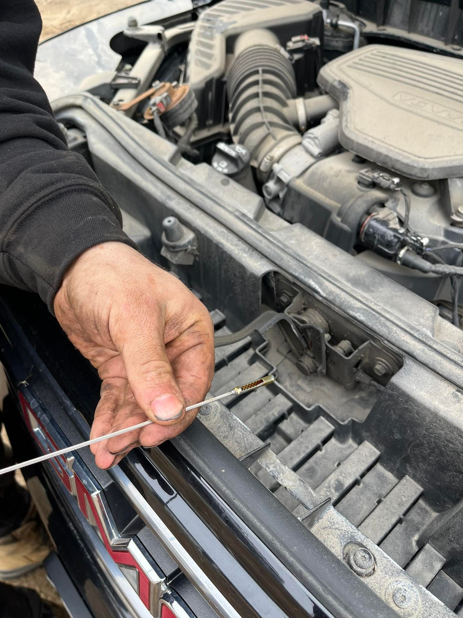 Hand holding a zip tie near a car engine bay and radiator support | Penner Auto