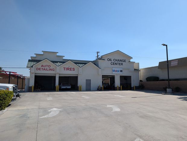 Auto repair garage with white facade and open service bays under a clear blue sky