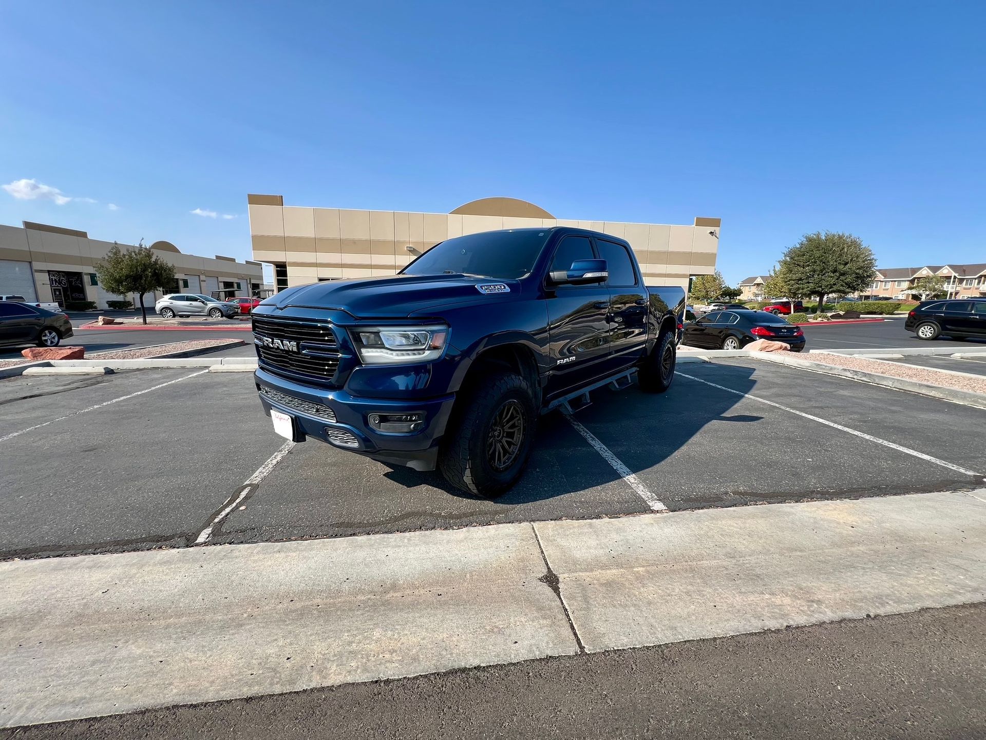 Blue lifted pickup truck parked in a parking lot under a clear sky