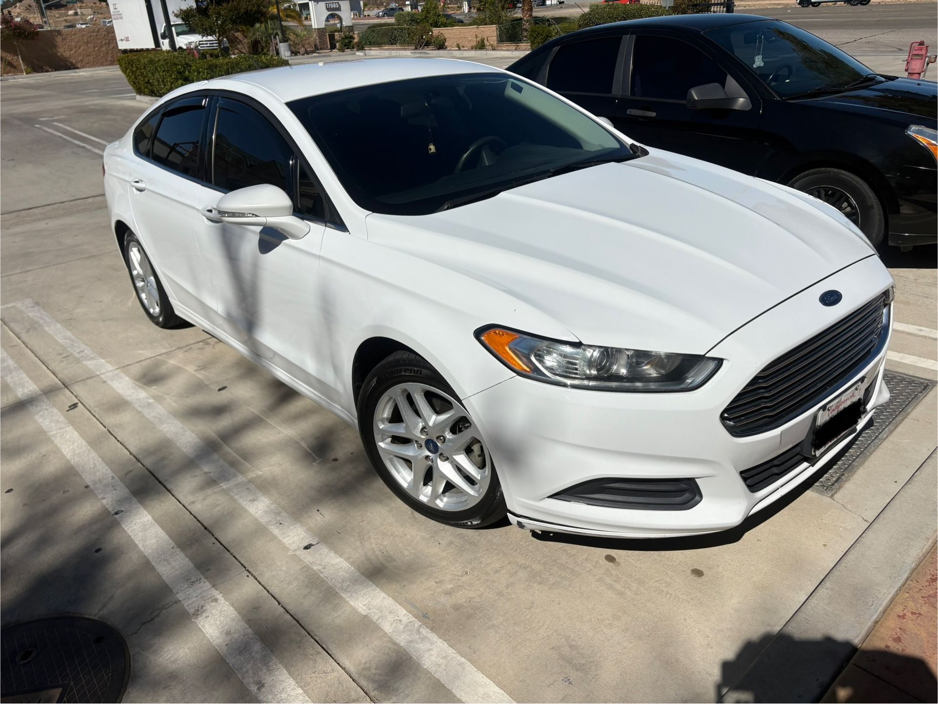 White sedan parked in a parking lot, front-right view, with tinted windows and silver wheels