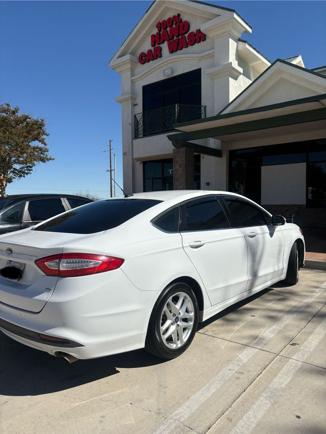 White sedan parked outside a dealership on a sunny day