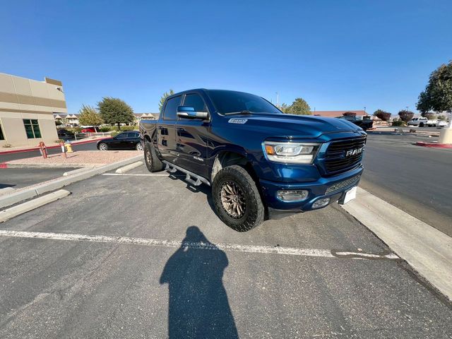 Blue pickup truck parked in a sunlit parking lot near a curb and storefronts.