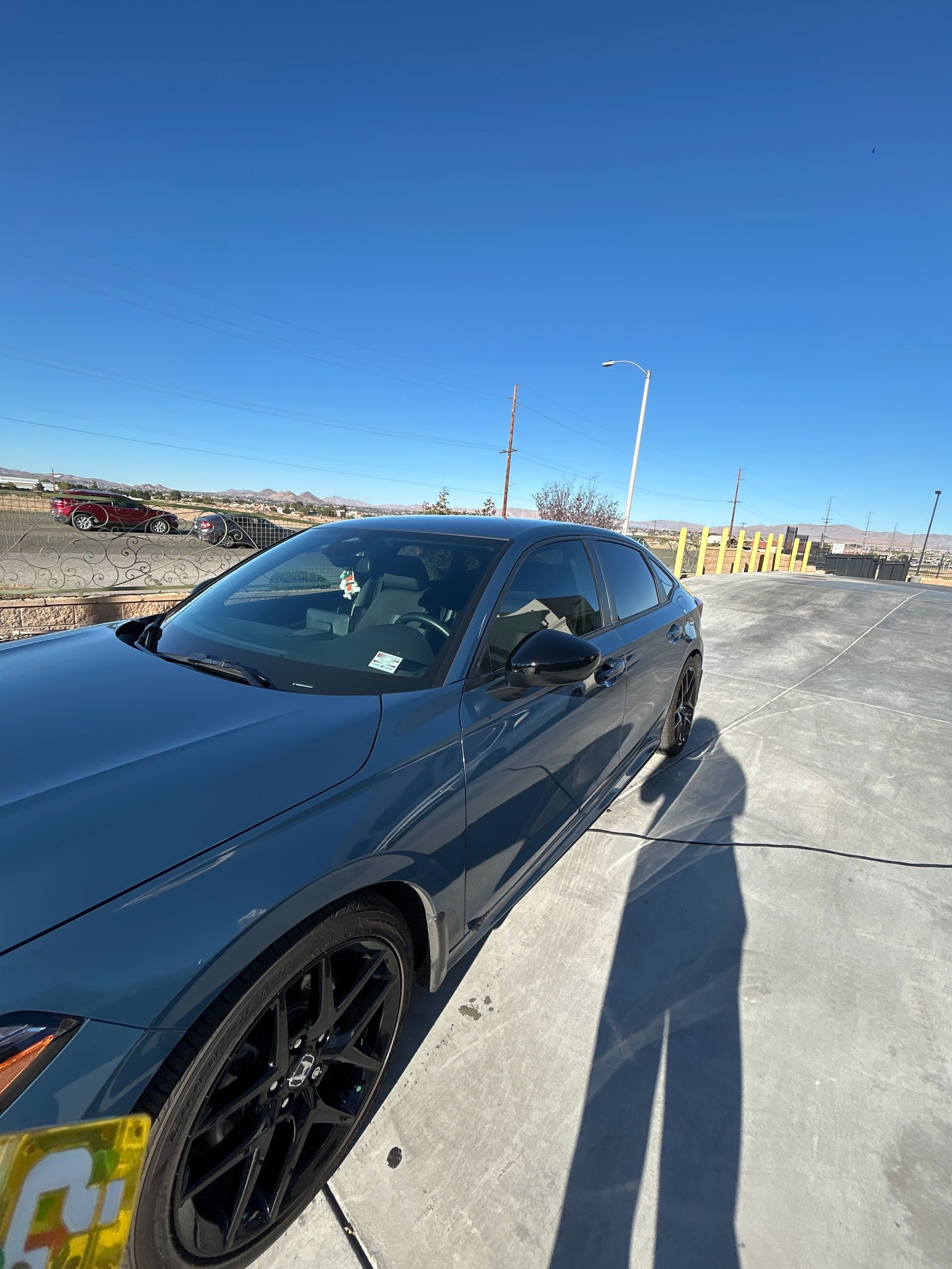 Black sports coupe parked in a sunny lot under a clear blue sky