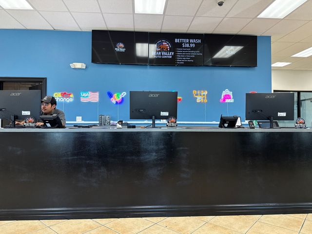 Front desk in a blue-walled lobby with computers and a staff member behind the counter