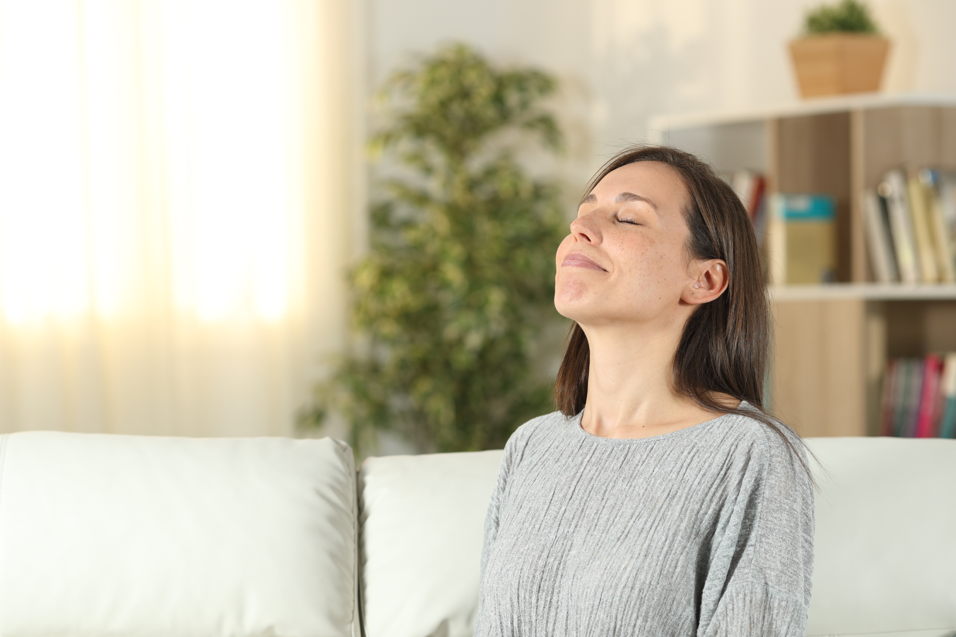 Now free of pollen allergy symptoms, a woman breathes freely while having a relaxing time at home.