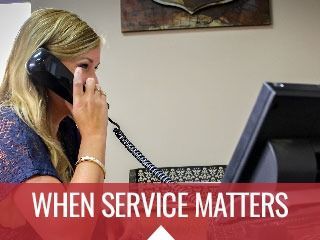 Woman on phone at desk with computer; banner reads “WHEN SERVICE MATTERS.”