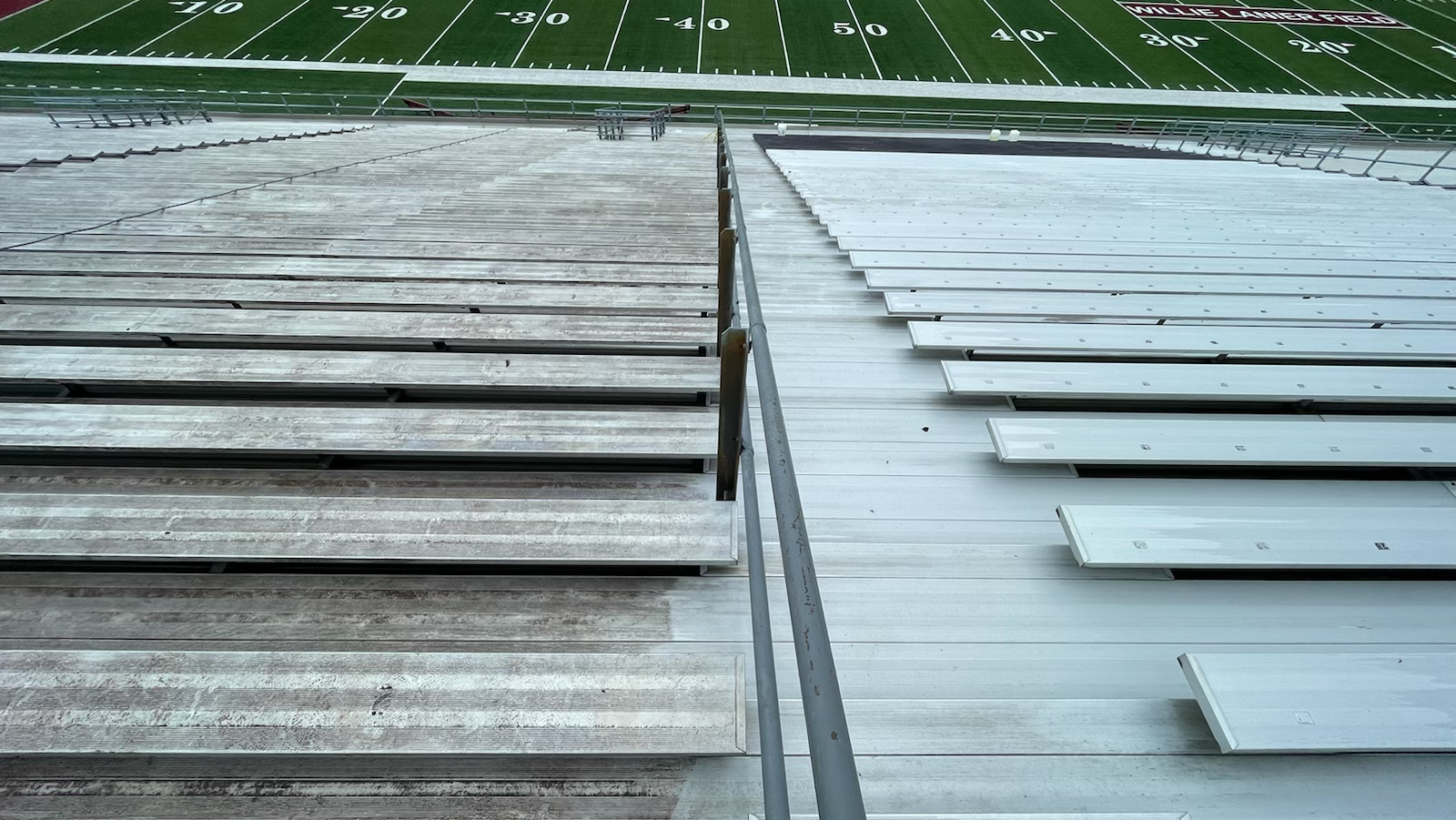 Weathered and painted roof panels split by a central seam, with a green field in the background