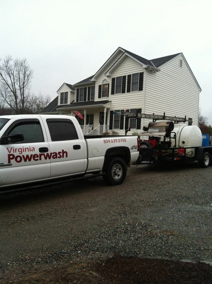 Virginia Powerwash truck and trailer parked beside a white house on a cloudy day