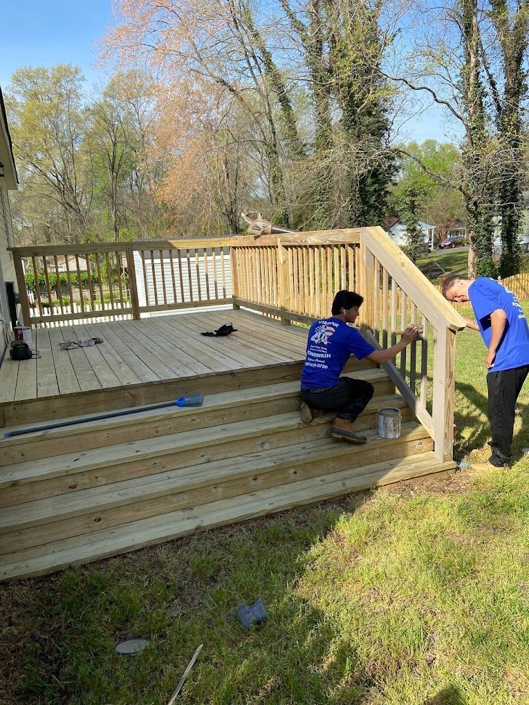 Two people installing a wooden deck railing in a grassy backyard.