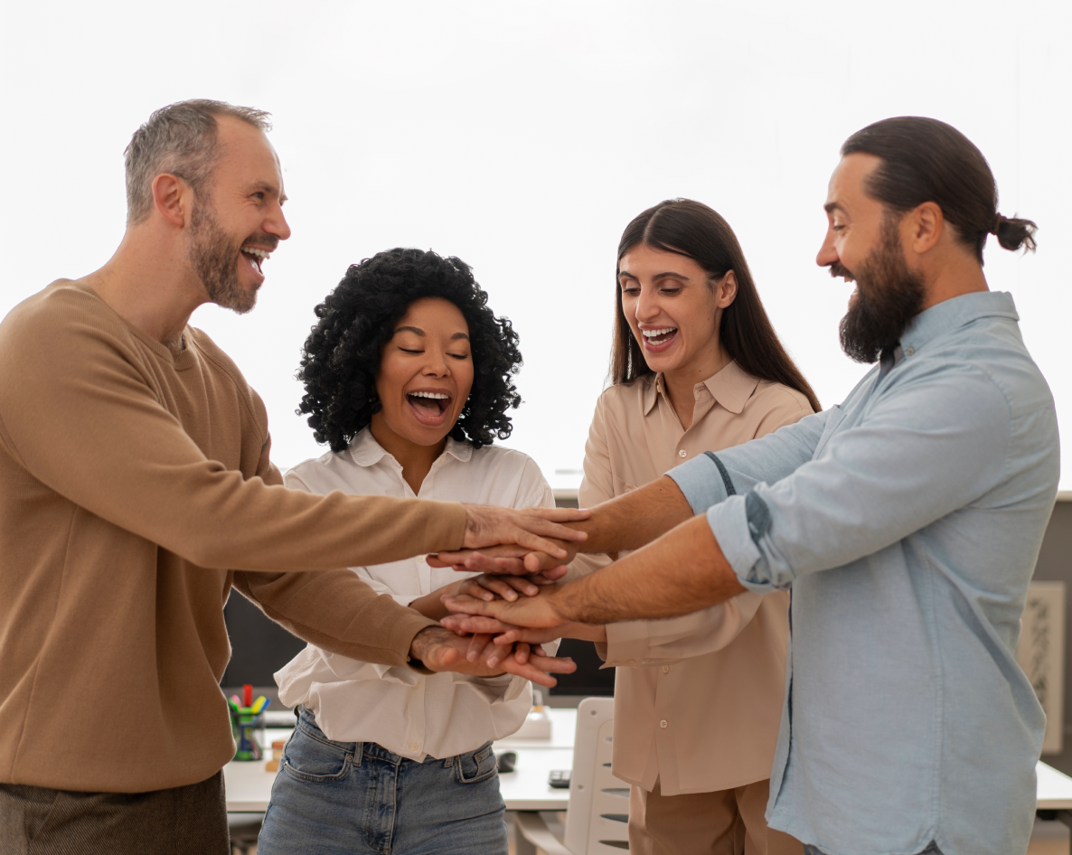 A group of people are putting their hands together in an office.