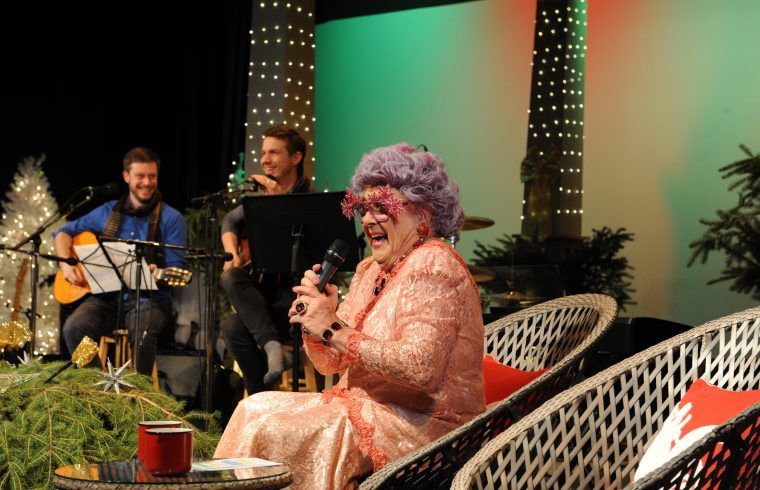 A man is playing a guitar and a woman is singing into a microphone.