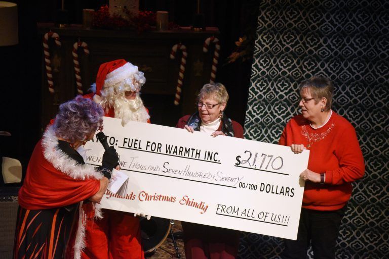 A group of people holding a check that says ' fuel for warmth inc ' on it