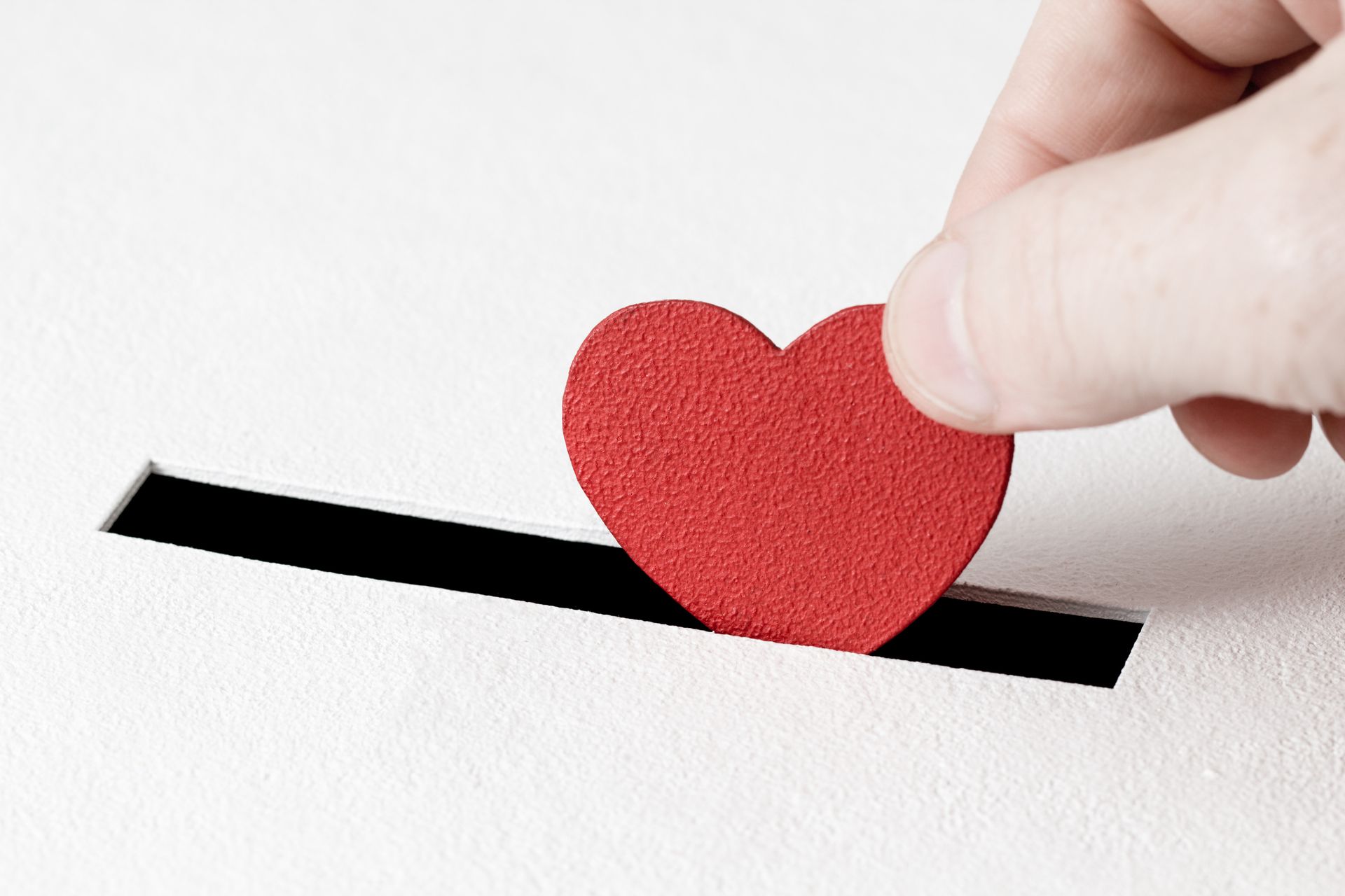 A person is putting a red heart in a box.
