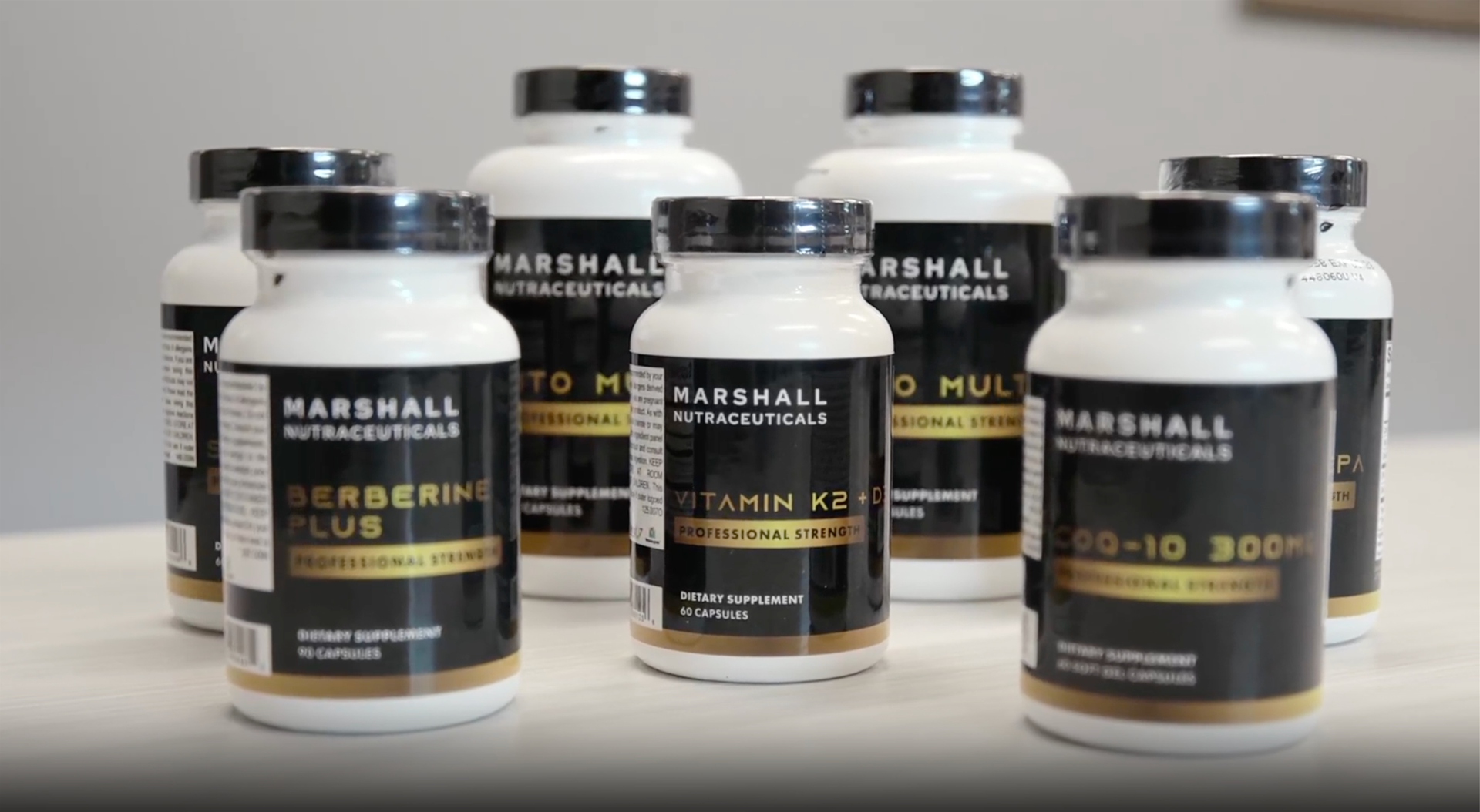 Five Marshall Nutraceutical supplement bottles with black caps, arranged in a row on a white background