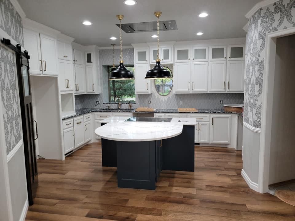 A kitchen with white cabinets and a large island in the middle.