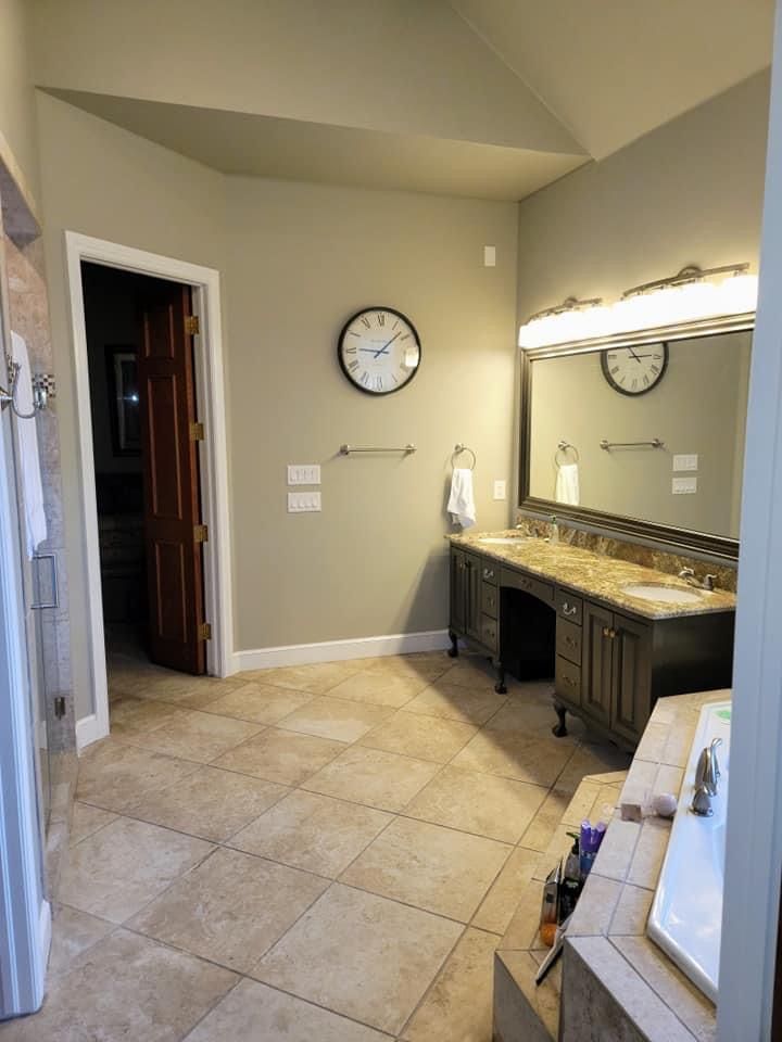 A bathroom with two sinks and a clock on the wall.
