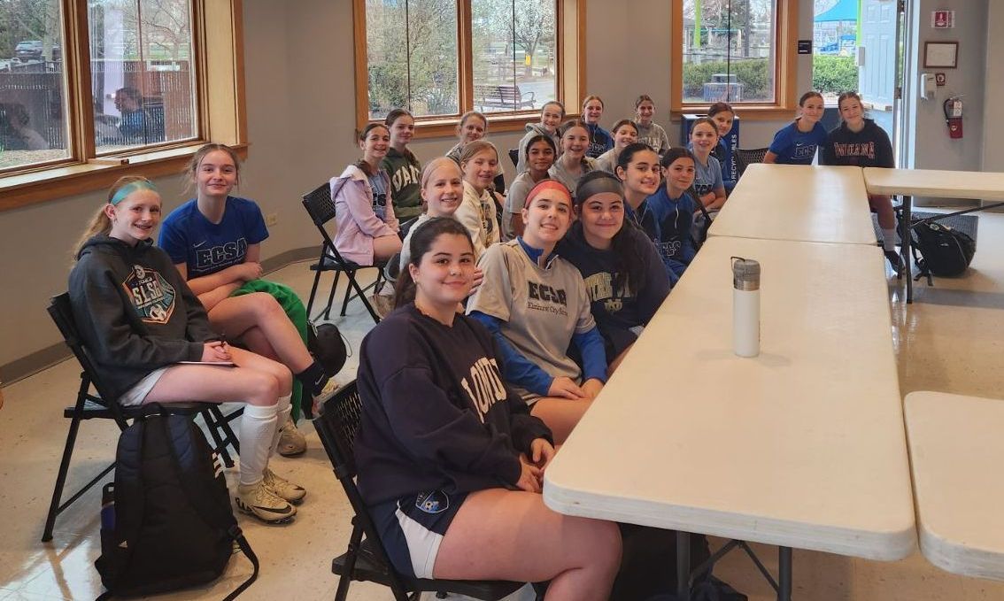 A group of young girls are sitting at tables in a room.