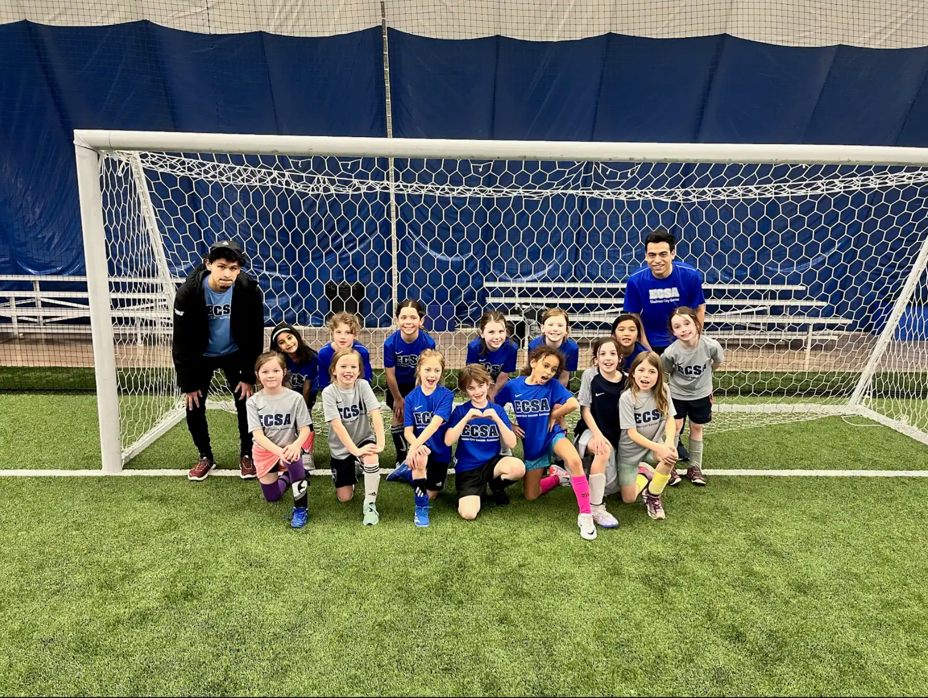A group of children are posing for a picture on a soccer field.