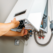 A person is fixing a water heater on a wall