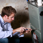 A man is fixing a furnace with a screwdriver.