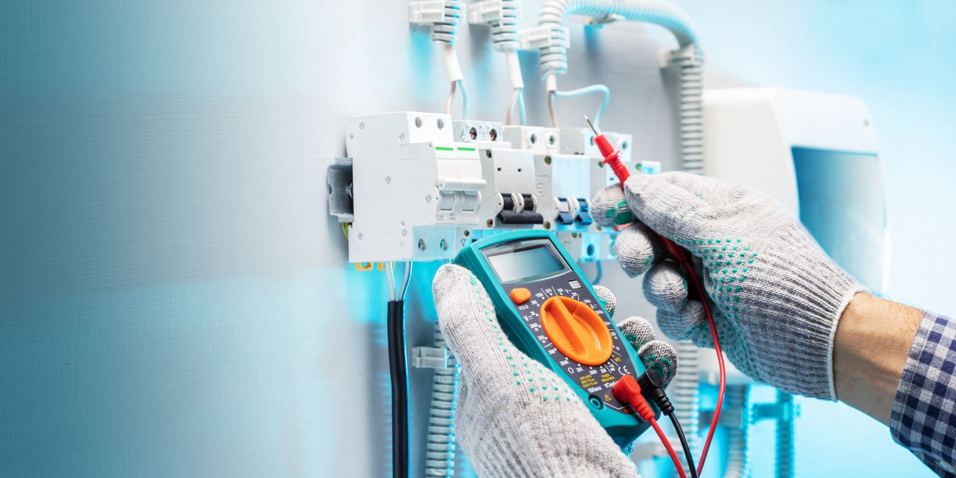 An electrician is using a multimeter to test an electrical circuit.