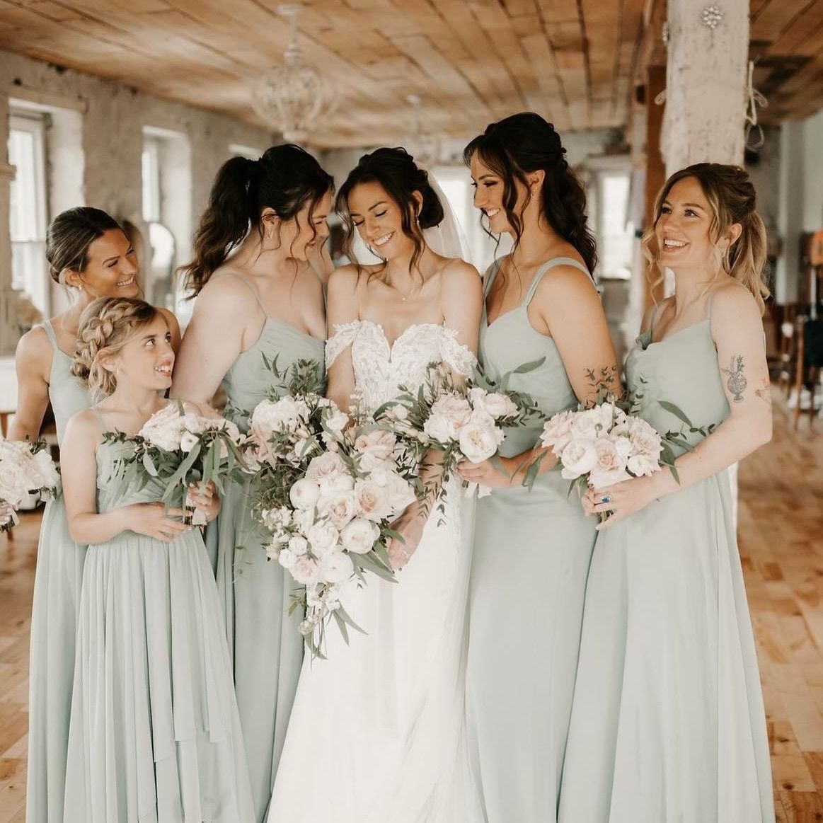 A bride and her bridesmaids are posing for a picture in a room.