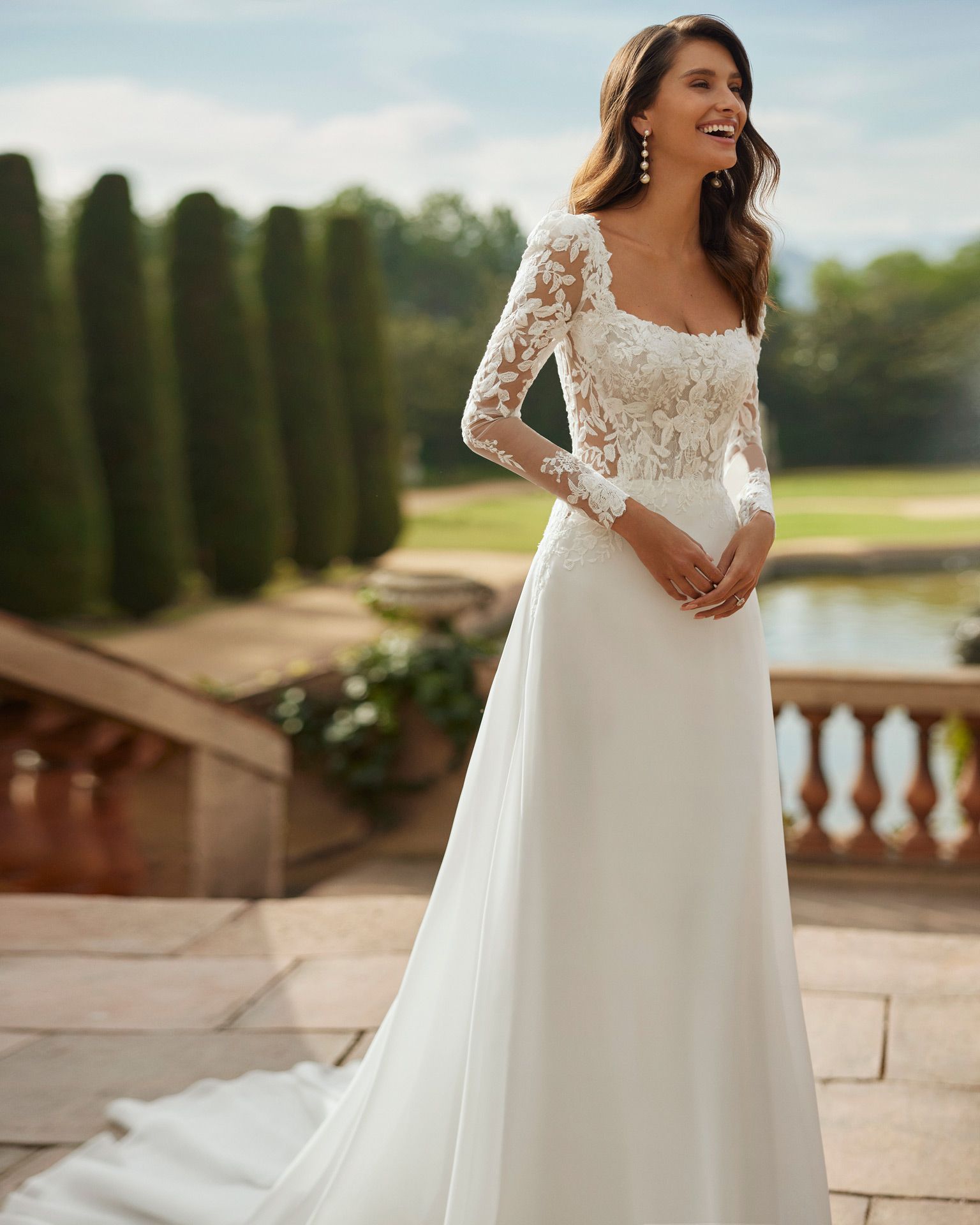 A woman is wearing a white wedding dress with long sleeves.