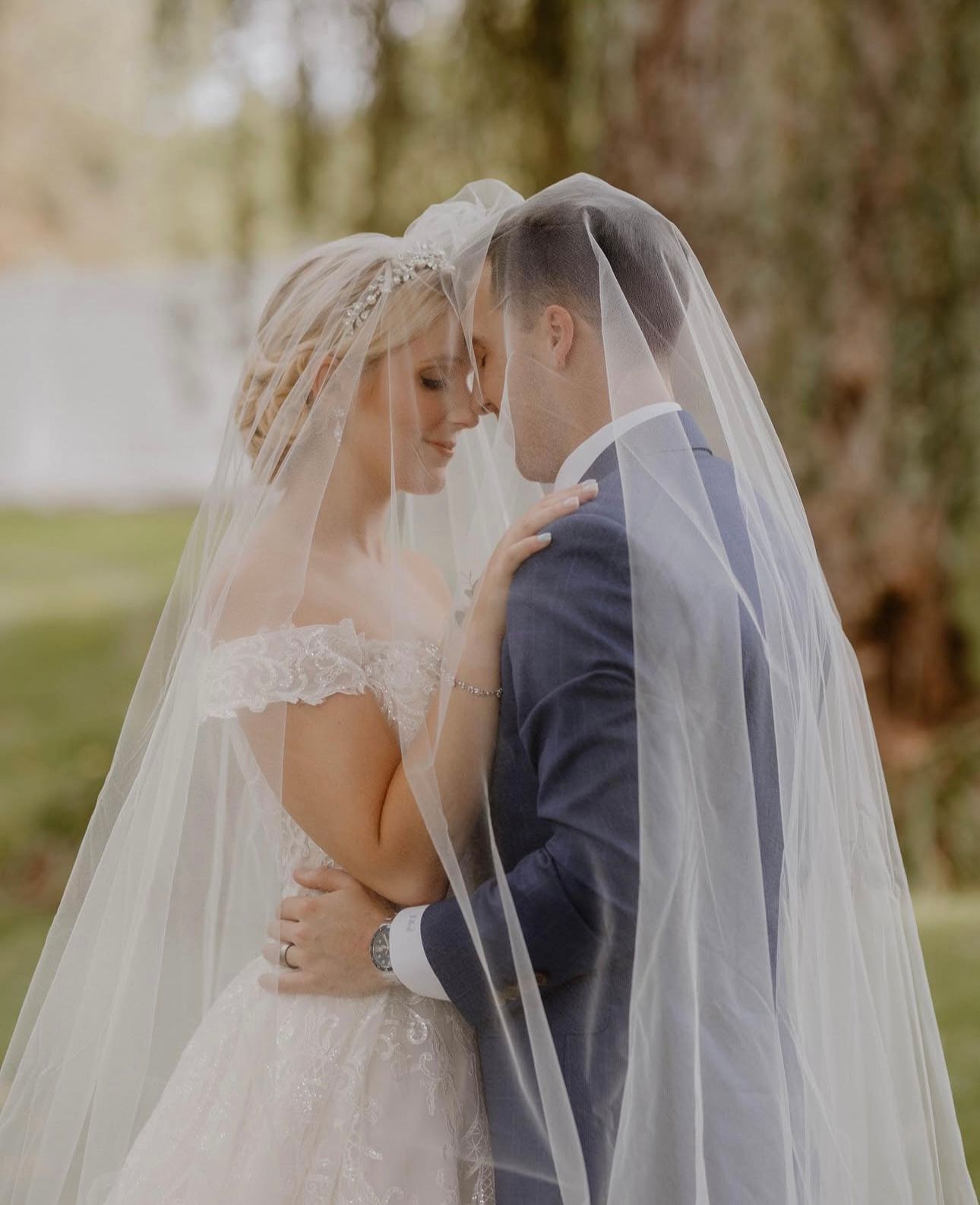 A bride and groom are standing next to each other under a veil.