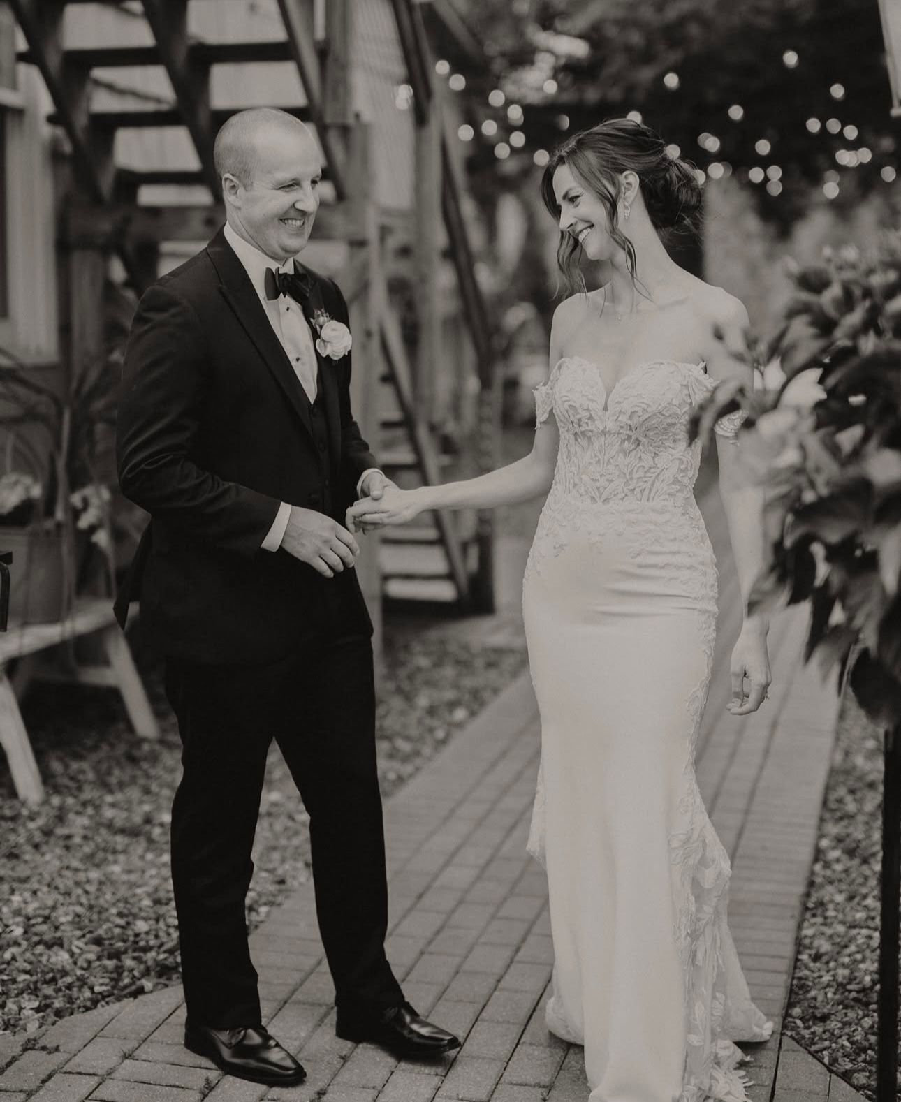 A black and white photo of a bride and groom holding hands.
