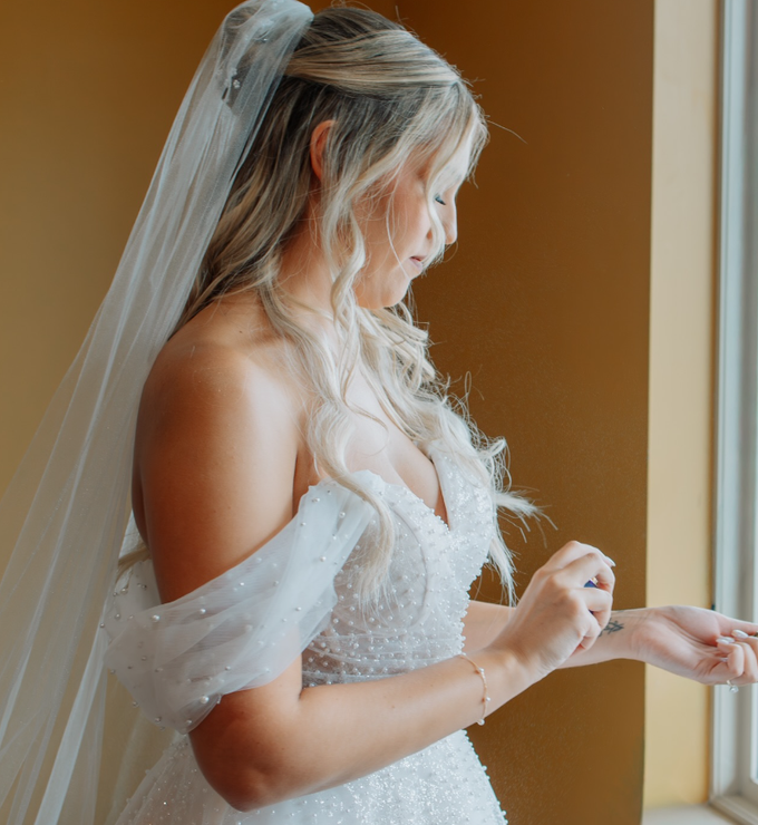A woman in a white wedding dress is standing in front of a mountain.