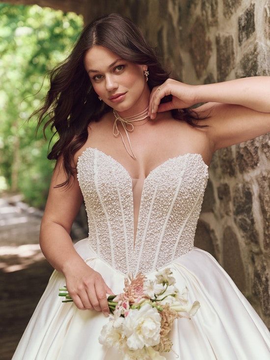 A woman in a wedding dress is holding a bouquet of flowers.