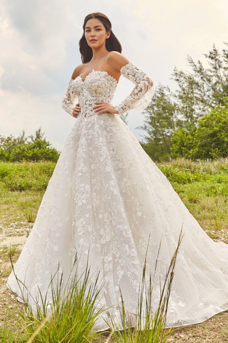 A woman in a white wedding dress is standing in a field.