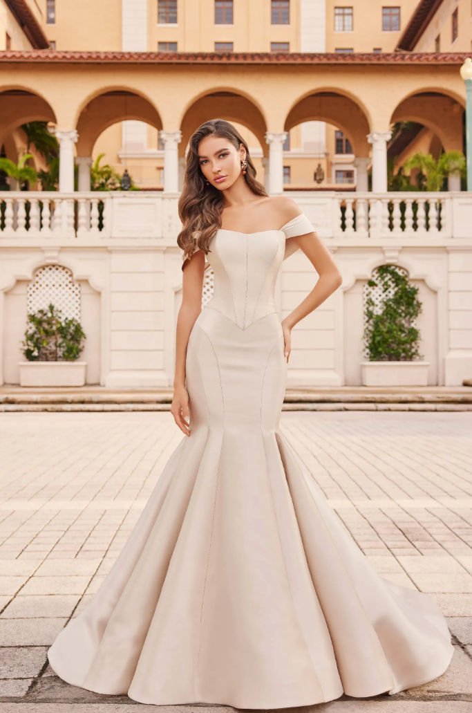 A woman in a white wedding dress is standing in front of a building.