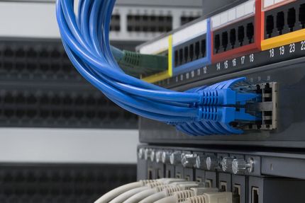 Blue-tinted rack of network switches with Ethernet cables connected.