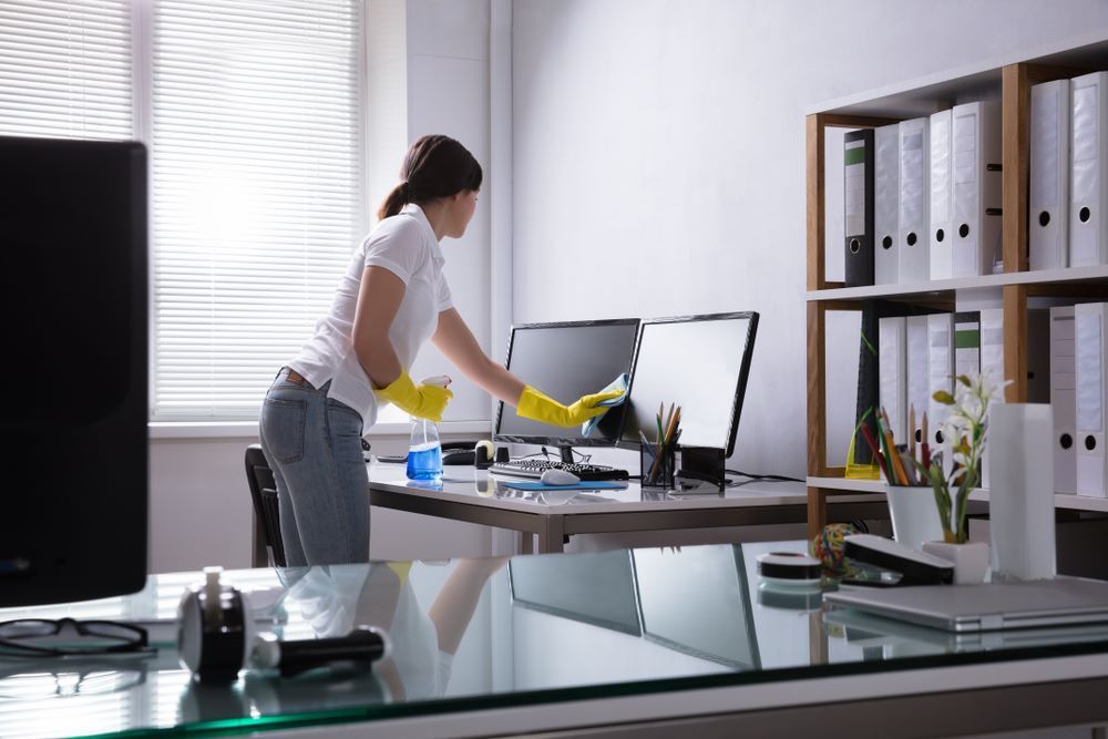 A Woman is Cleaning a Computer Monitor in an Office — O & D House Wash & Cleaning Services in Highfields, QLD