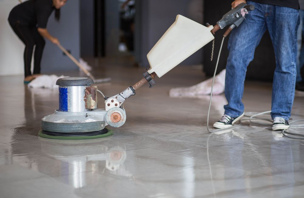 A Man is Polishing a Floor With a Machine — O & D House Wash & Cleaning Services in Highfields, QLD