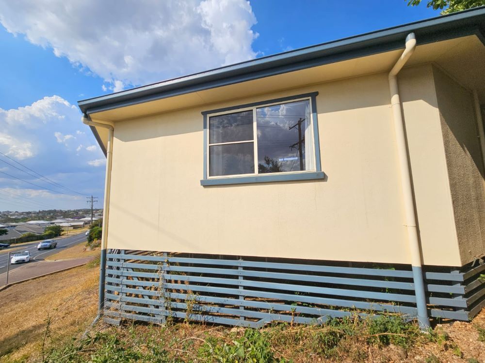 A small white house with a window on the side of it. — O & D House Wash & Cleaning Services in Highfields, QLD