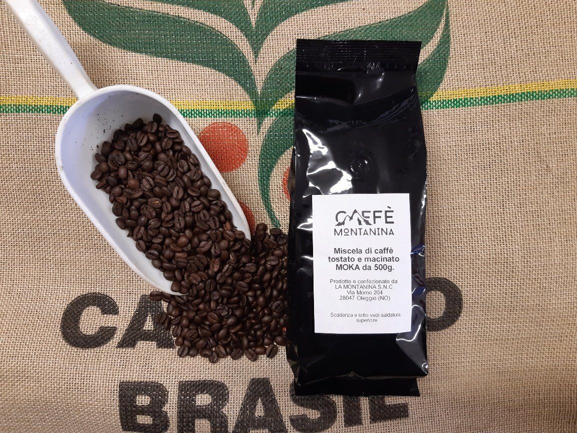 Un misurino di plastica bianca pieno di chicchi di caffè tostati scuri accanto a una confezione di caffè Café Montanhas, il tutto su un sacco di iuta.