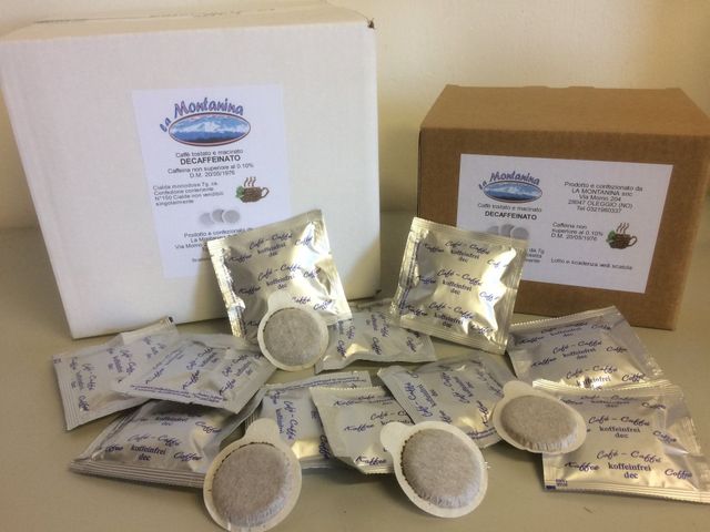 Due scatole di capsule di caffè "Mountain Paradise" circondate da diverse capsule di caffè sfuse, alcune avvolte singolarmente in fogli di alluminio.