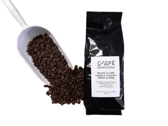 Un sacchetto nero di chicchi di caffè Caffè Mantanina accanto a un cucchiaio bianco traboccante di chicchi di caffè tostati scuri.
