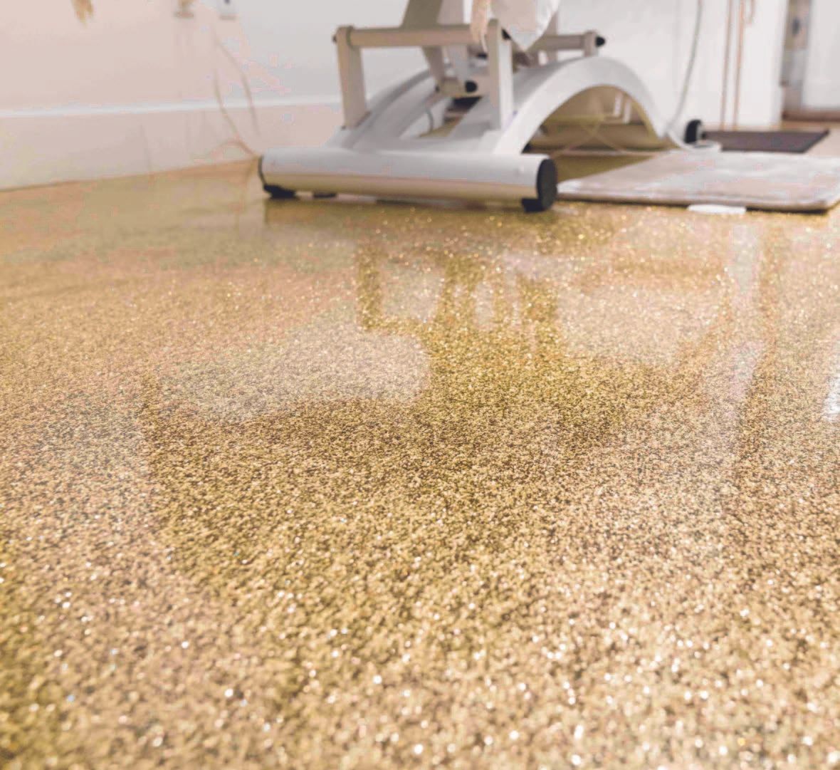 Floor buffer polishing a speckled gold floor in a room