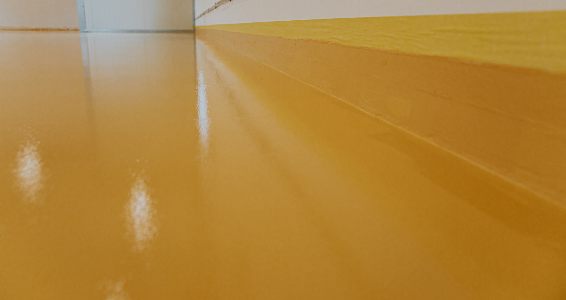 Shiny orange indoor floor with reflections and a wall in the background