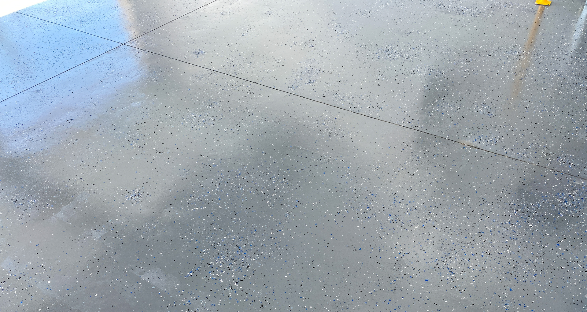 Close-up of a gray concrete floor with small speckles and a yellow object at the top edge.
