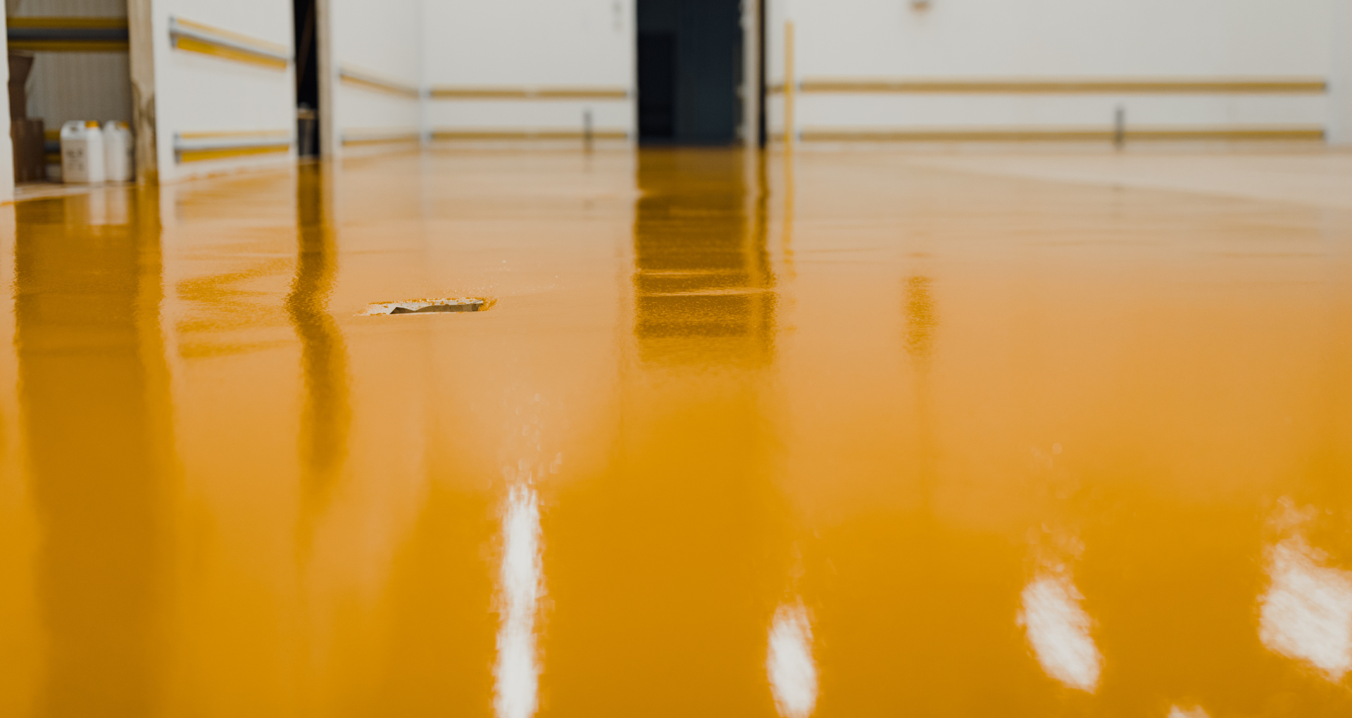 Glossy orange floor in an empty indoor room with columns and reflected light.