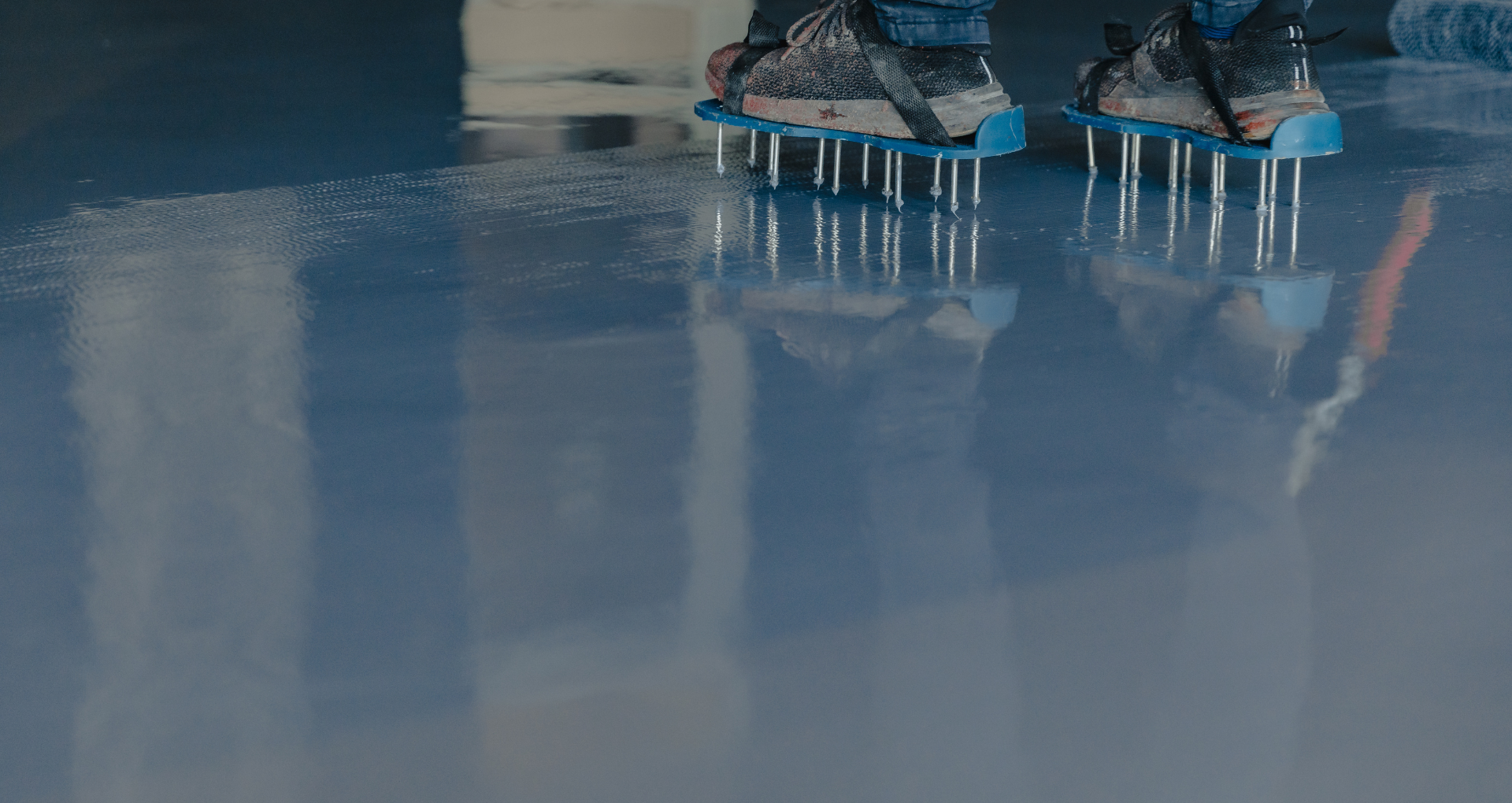 Close-up of feet on blue ice skates gliding across a glossy ice rink surface