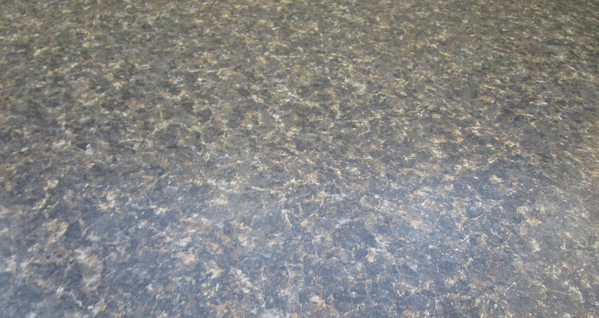 Close-up of a speckled gray and tan textured surface, likely stone or carpet.