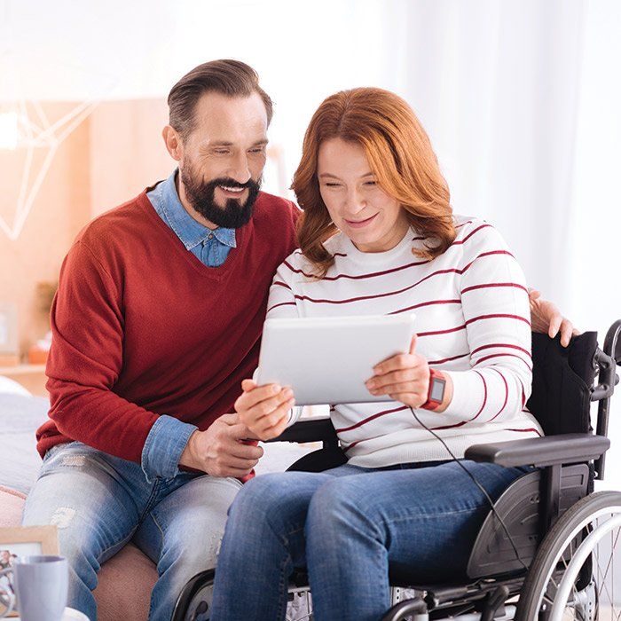 Woman With Disability Looking at the Tablet With Her Husband