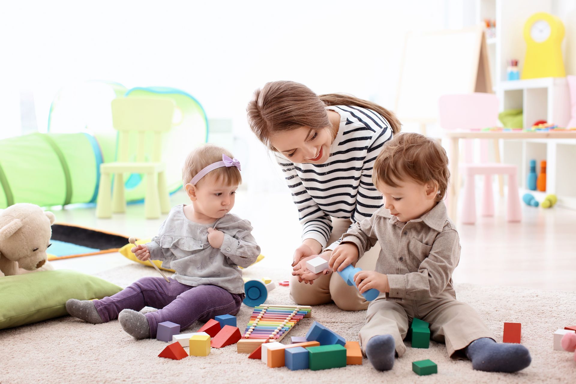 Young nanny playing with little children, indoors. Young nanny playing with little children, indoors.