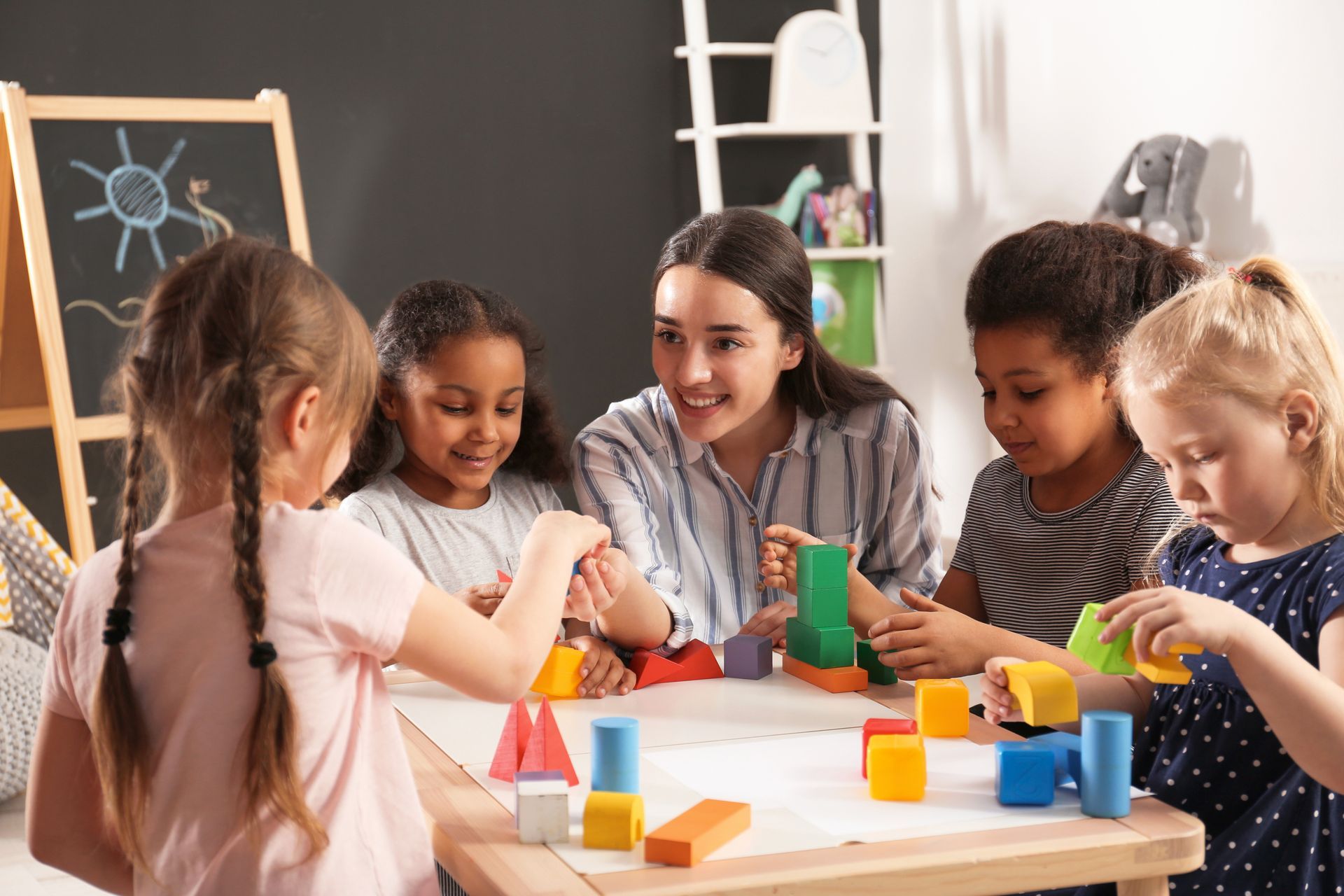 Four children building with colored blocks at a classroom table